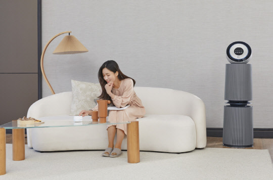 LG전자 모델이 LG 퓨리케어 360˚ 공기청정기 알파(사진 오른쪽)와 연동해 사용하는 인공지능 센서를 소개하고 있다. <LG전자 제공>